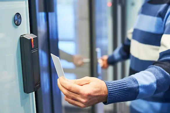 Man using access control card on card reader to gain secure entry into a restricted room