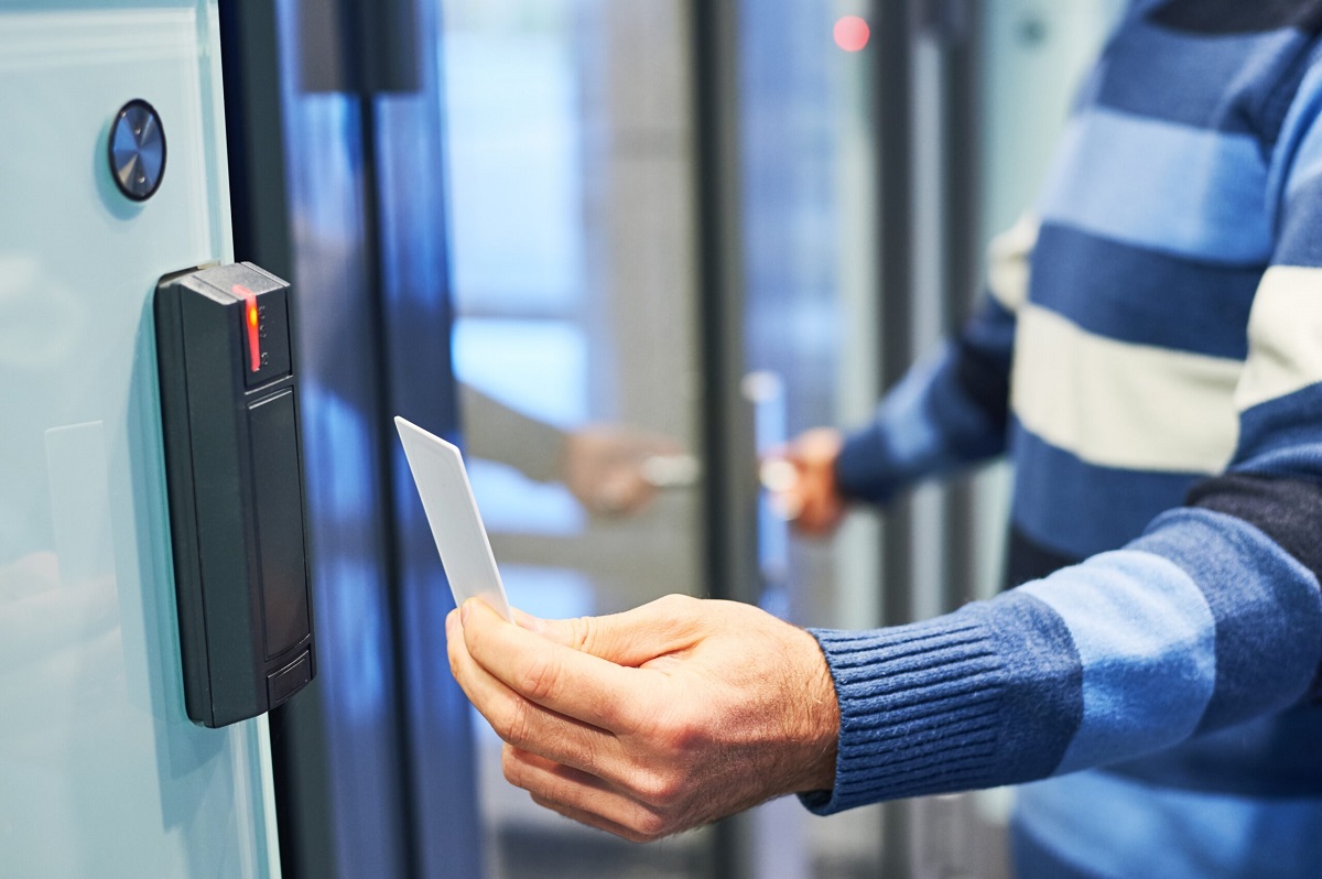 Man using access control card on card reader to gain secure entry into a restricted room