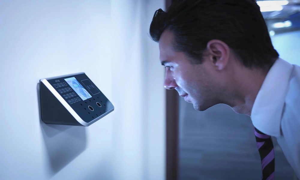 Man using facial recognition access control system to scan face for secure entry into restricted room.
