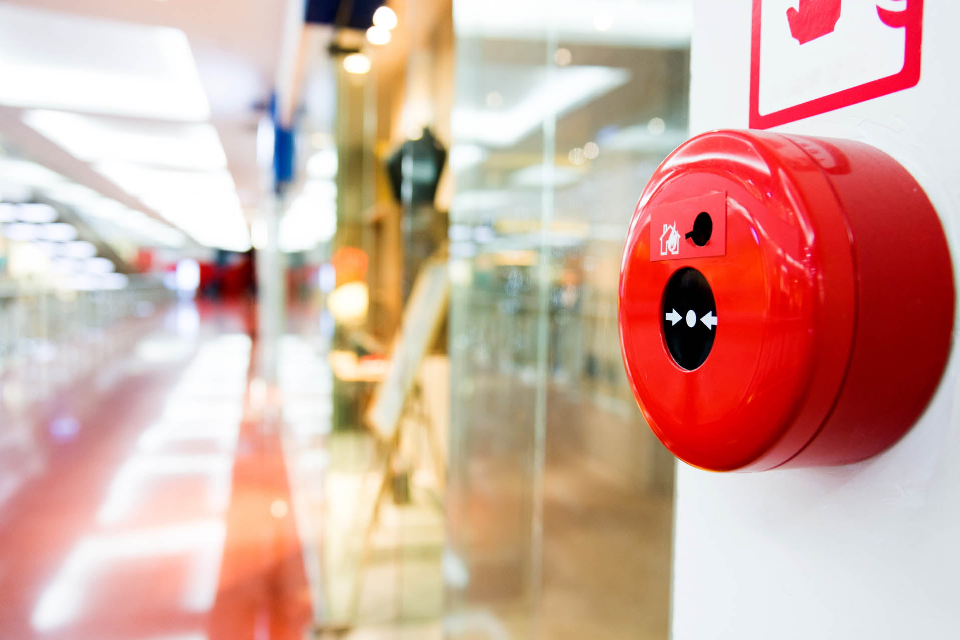 Red fire alarm installed in a large building hallway for enhanced fire detection and emergency alert system