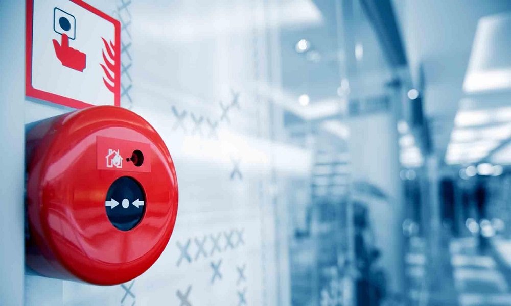 Red fire alarm mounted in a corporate building hallway for emergency alert and fire safety compliance