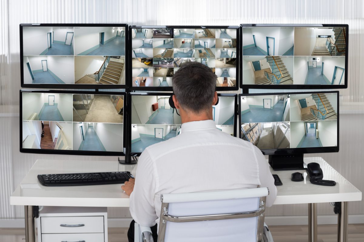 Operator monitoring surveillance footage in a compact security control room with multiple CCTV and security system screens