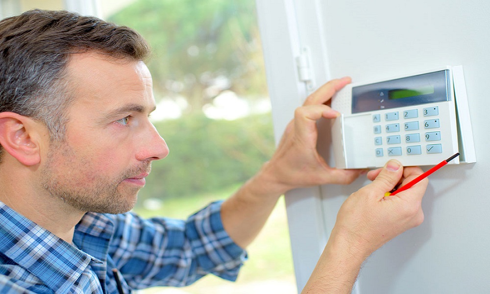 Technician installing intrusion detection system for enhanced building security and unauthorized access prevention