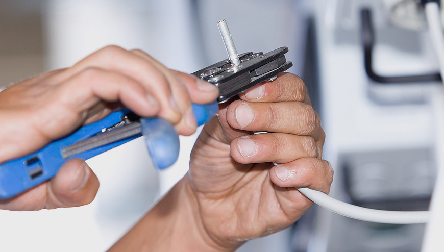 Technician repairing a network cable as part of system maintenance services